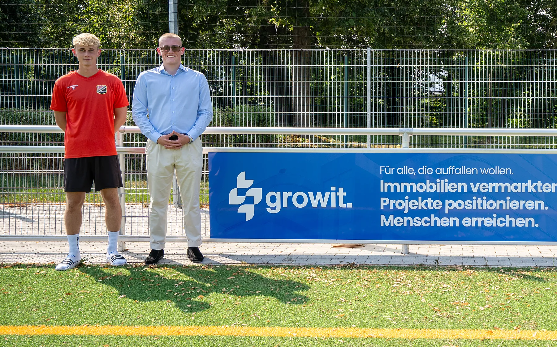 Ein Spieler des VfB Germania Halberstadt und ein Growit-Mitarbeiter neben dem Growit-Banner am Spielfeldrand