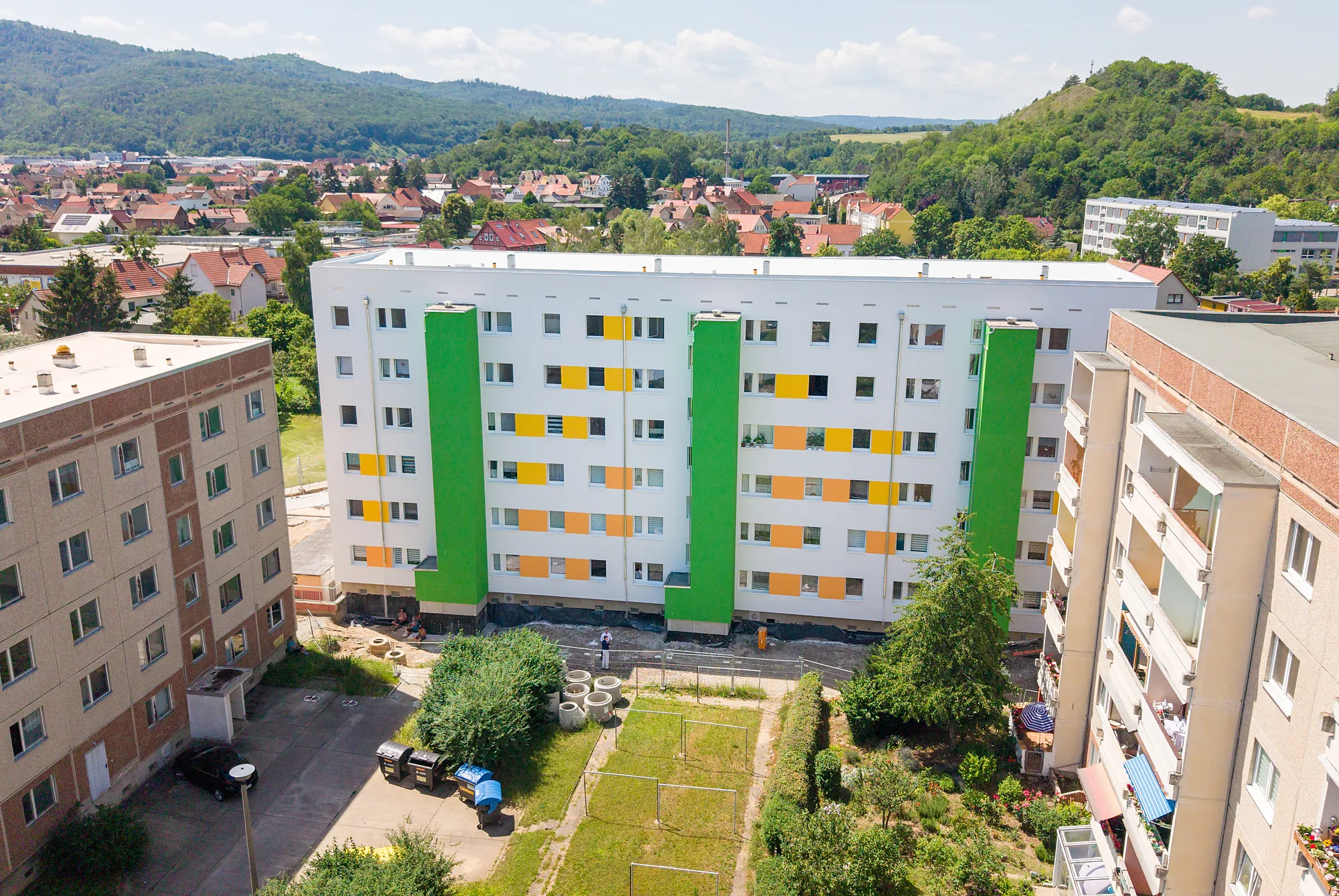 Sanierter Wohnblock der Wohnungsgenossenschaft Thale vor den Bergen des Harzes, Drohnenfoto